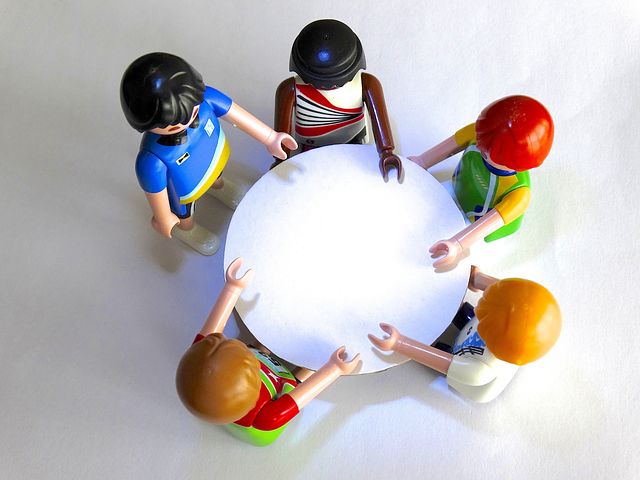 Playmobil-figuren stehen um einen Tisch und beraten sich